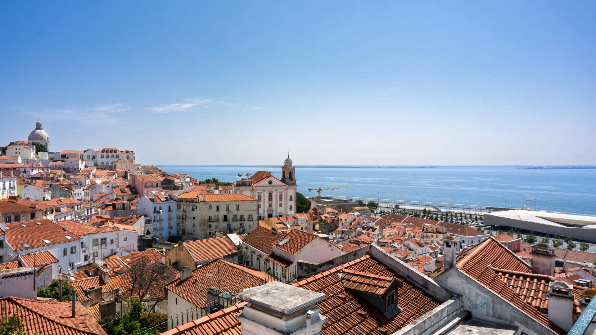 Vista panoramica del barrio de Alfama en Lisboa con tejados rojos y el rio Tajo