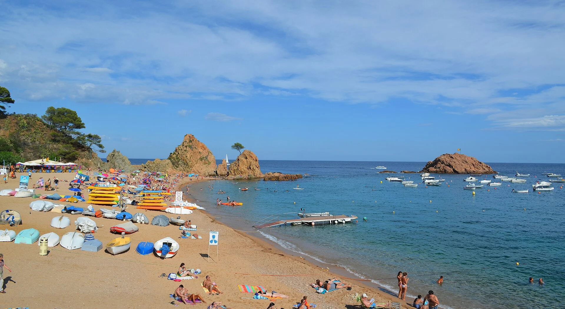 Sommerstrand mit Booten und Felsformationen am Mar Menuda in Tossa de Mar an der Costa Brava