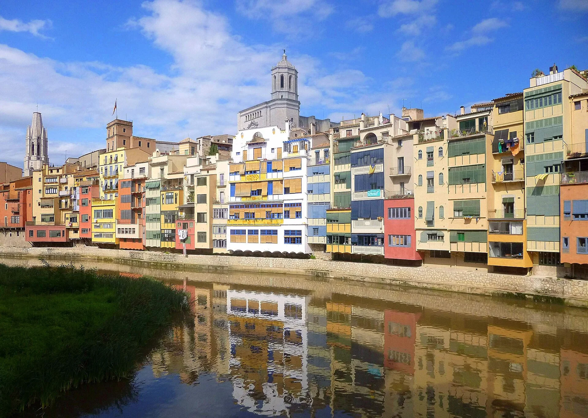 Bunte Häuser von Girona spiegeln sich im Fluss Onyar mit dem Kathedralenturm dahinter