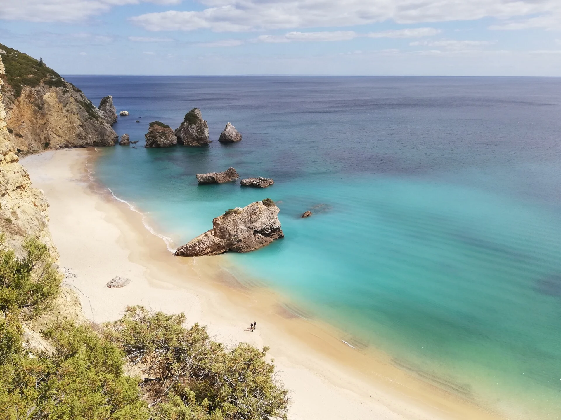 Arrábida Natural Park in Portugal with turquoise water beach surrounded by green limestone cliffs