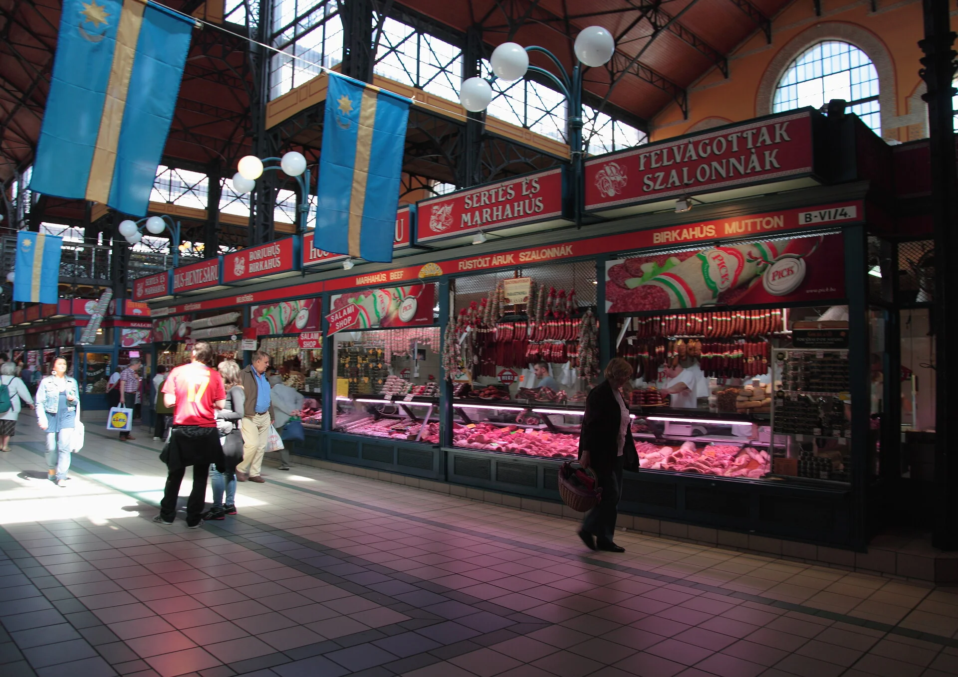Interior do Grande Mercado de Budapeste mostrando a estrutura ornamental de ferro e as coloridas barracas do mercado