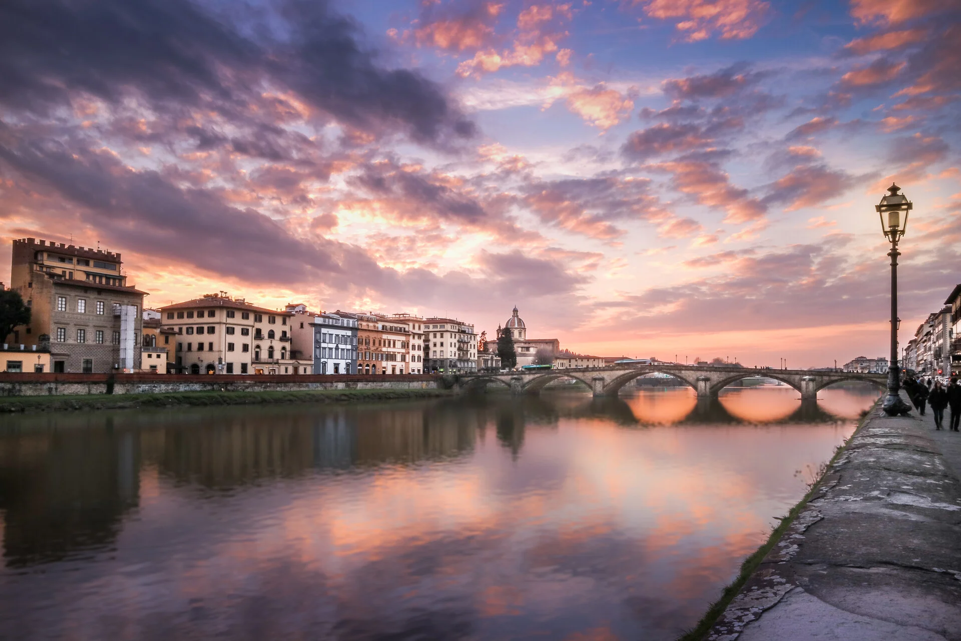 Sunset over the Arno River and a bridge in Florence seen from the Oltrarno riverbank