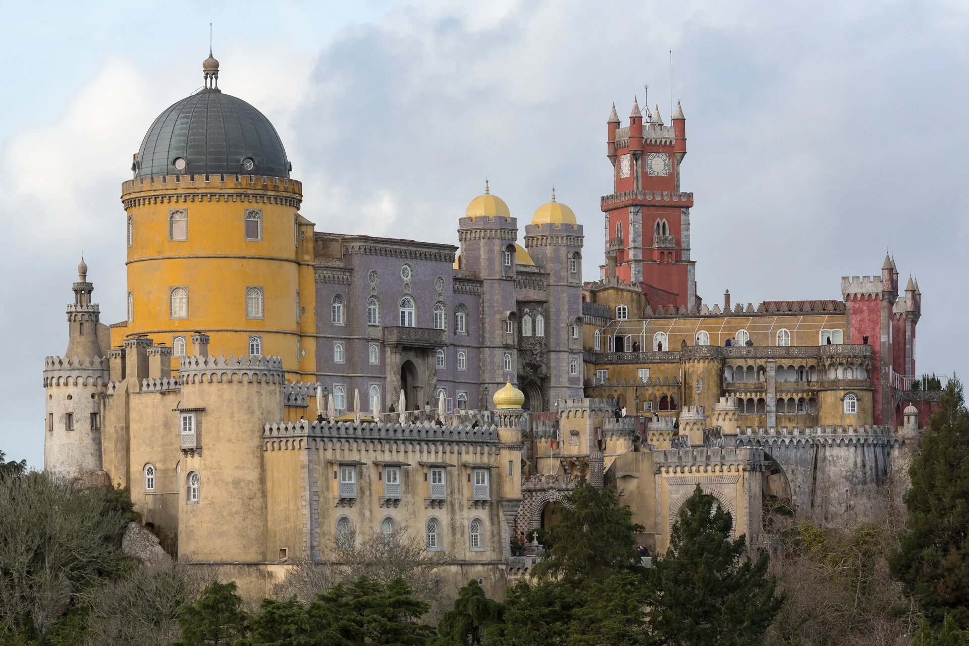 Colorido Palácio da Pena em Sintra com suas torres vermelhas e amarelas sobre colinas arborizadas