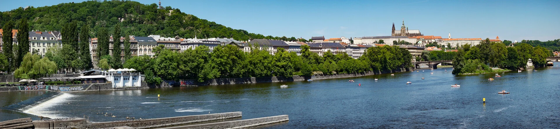 Wide panorama of the Vltava River through Prague with bridges and the historic Old Town skyline