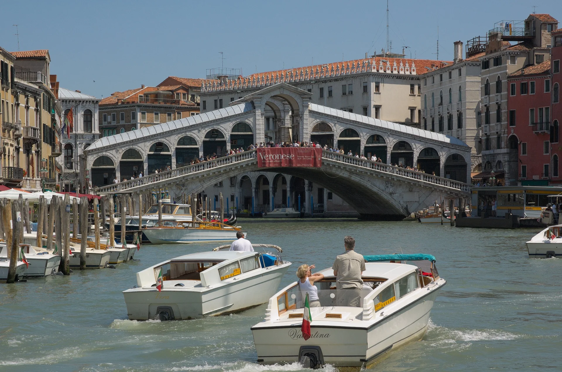 A Ponte de Rialto cruzando o Grande Canal em Veneza com táxis aquáticos passando por baixo
