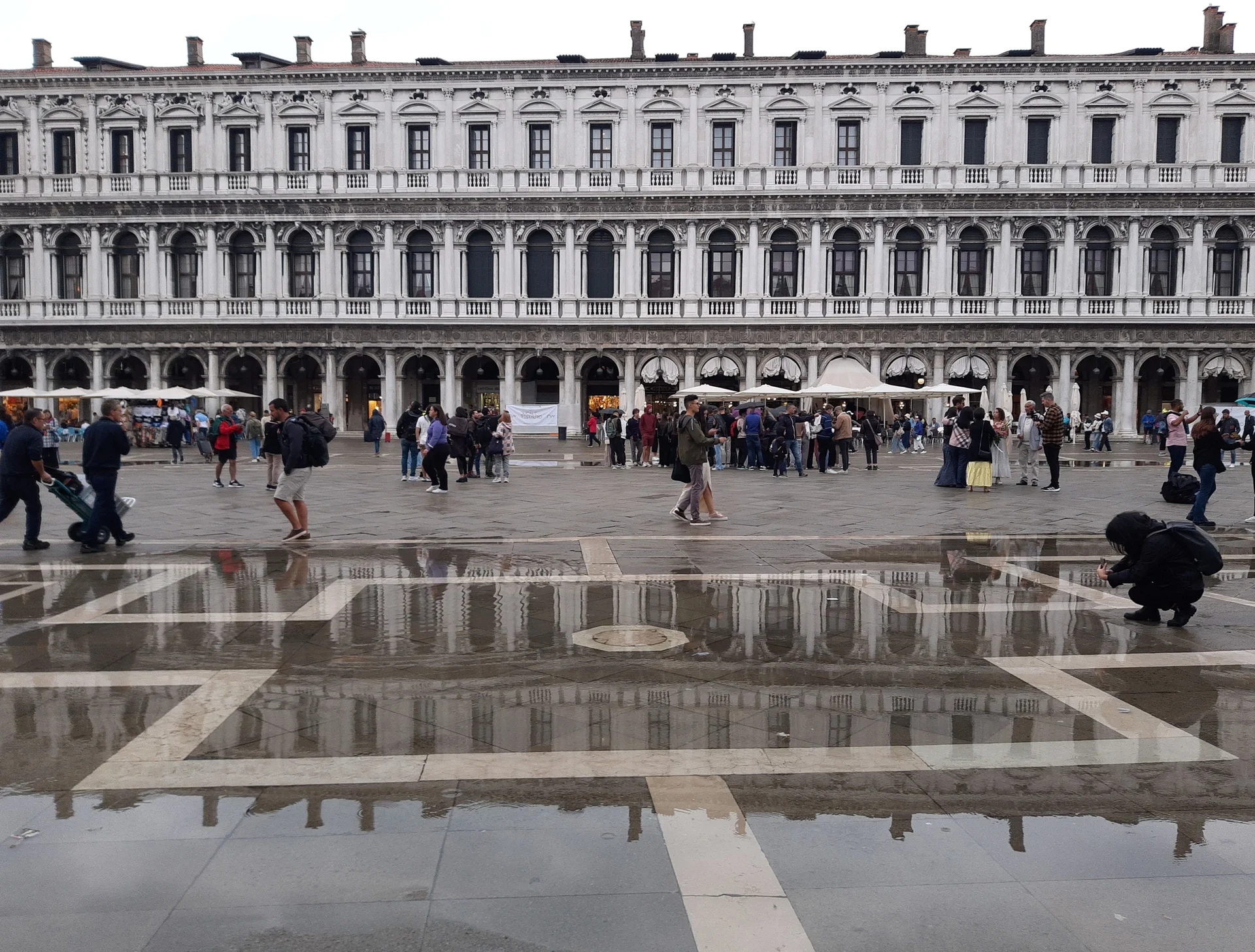 Os edifícios das Procuratie com arcadas da Praça de São Marcos em Veneza refletidos na água da chuva sobre a piazza