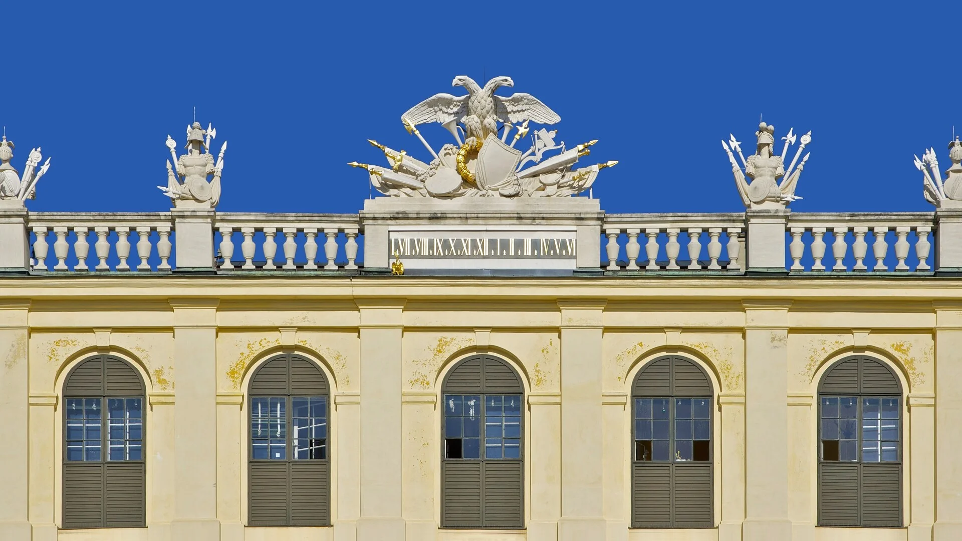 Fachada frontal do Palacio de Schoenbrunn em Viena com seu grande exterior amarelo e jardins bem cuidados