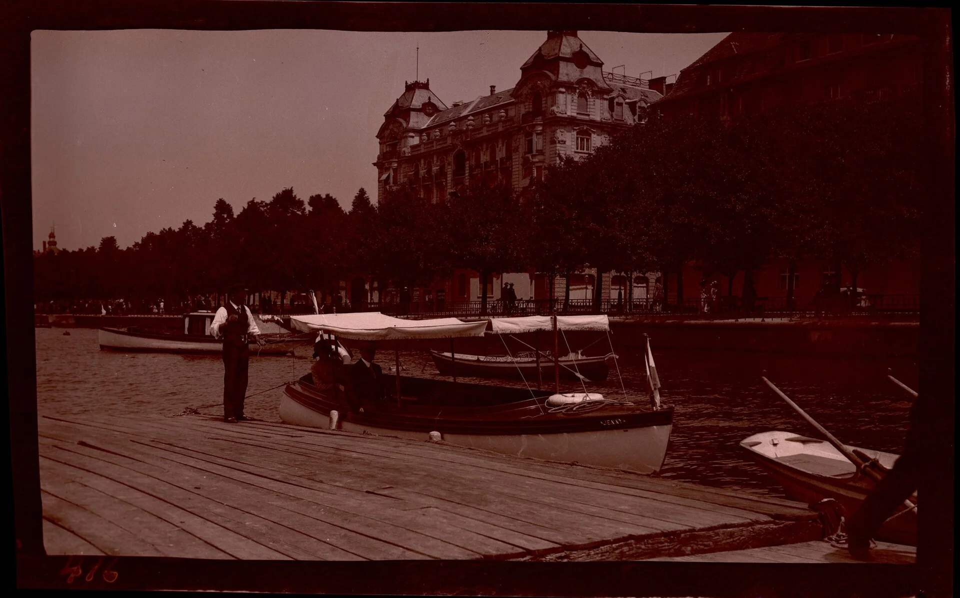 A passenger boat cruising on Lake Zurich with the lakeside promenade and hills in the background
