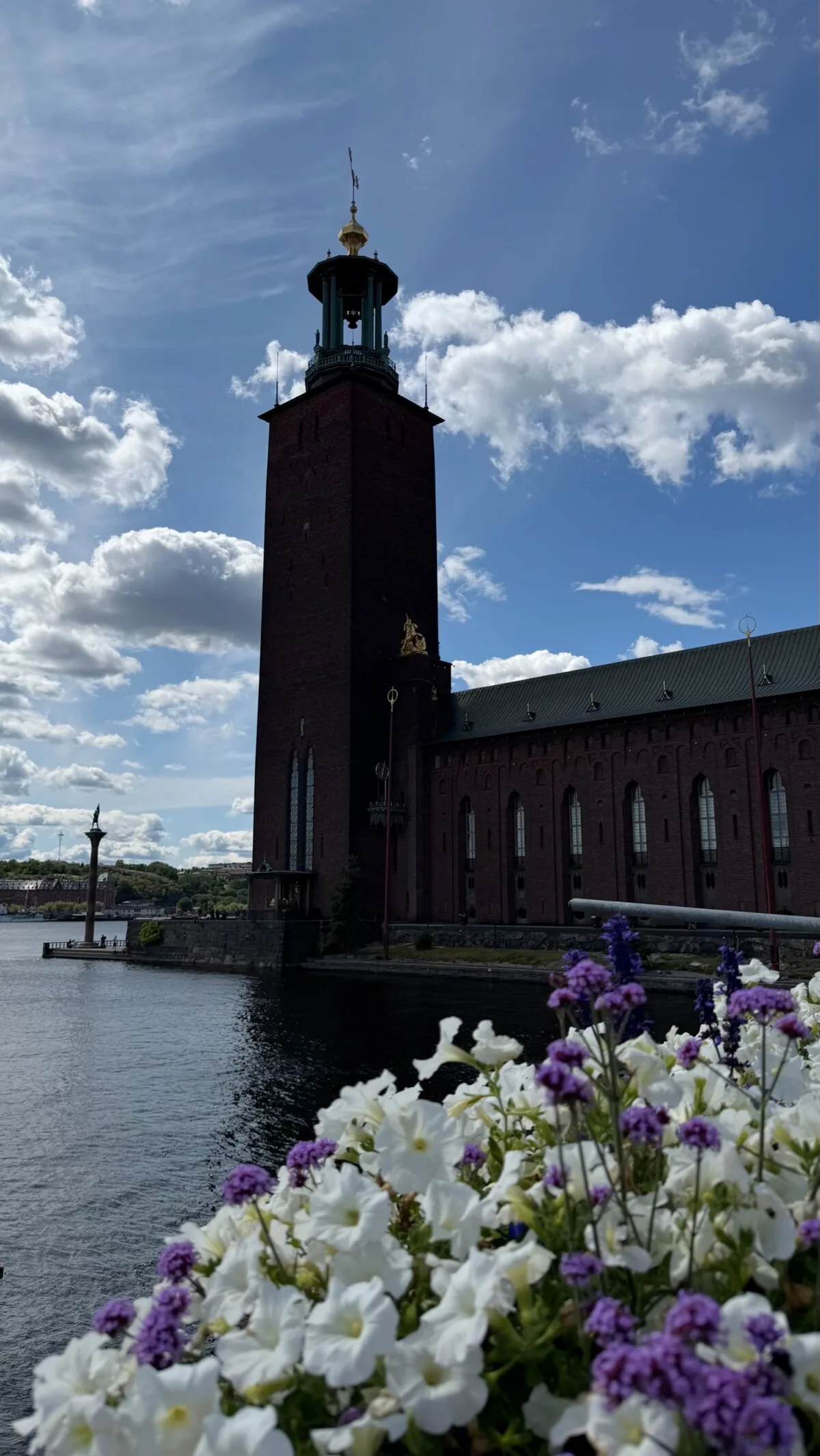 The red-brick tower of Stockholm City Hall with its three golden crowns against a blue sky