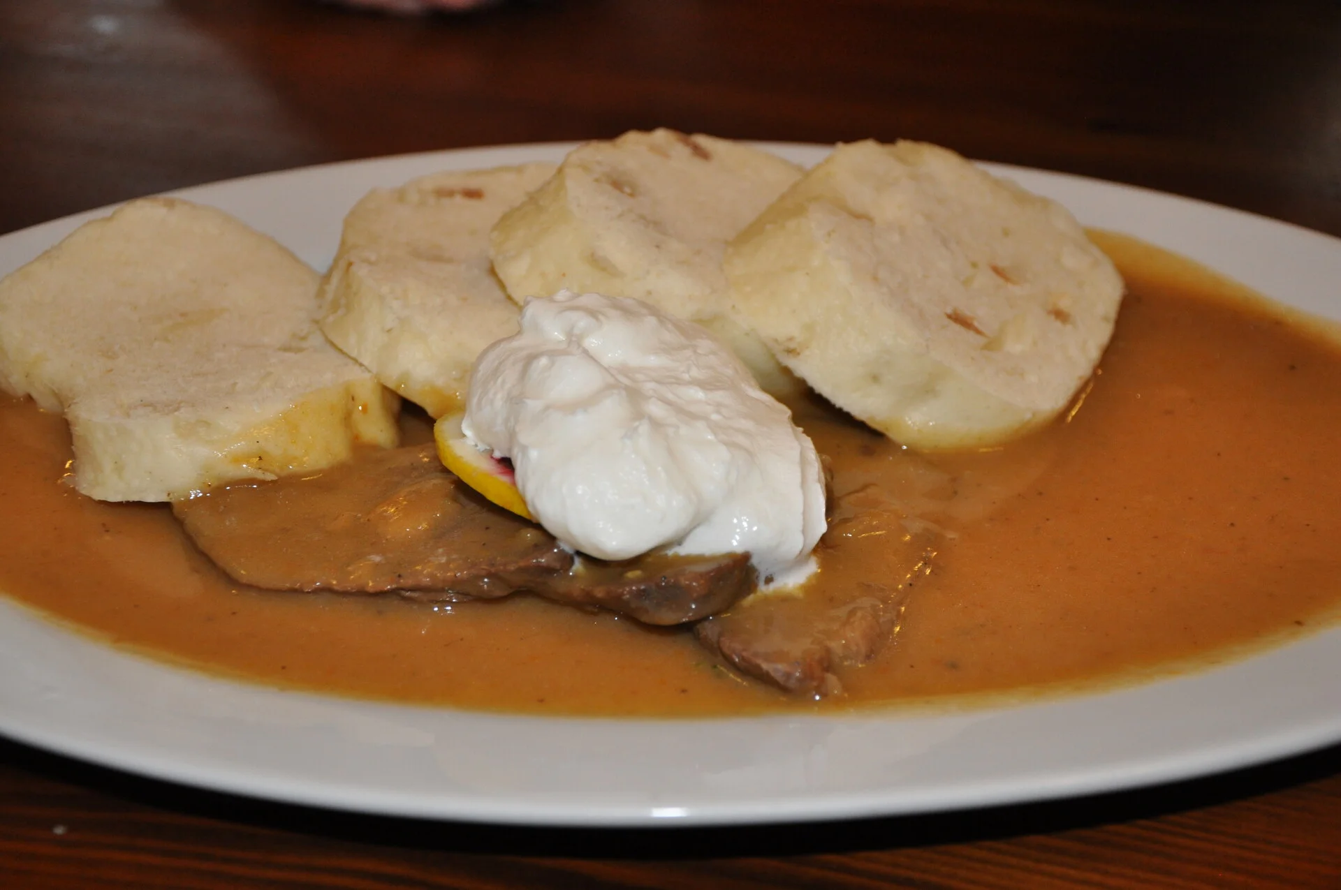 Traditional Czech svíčková with bread dumplings, cranberry sauce, and whipped cream