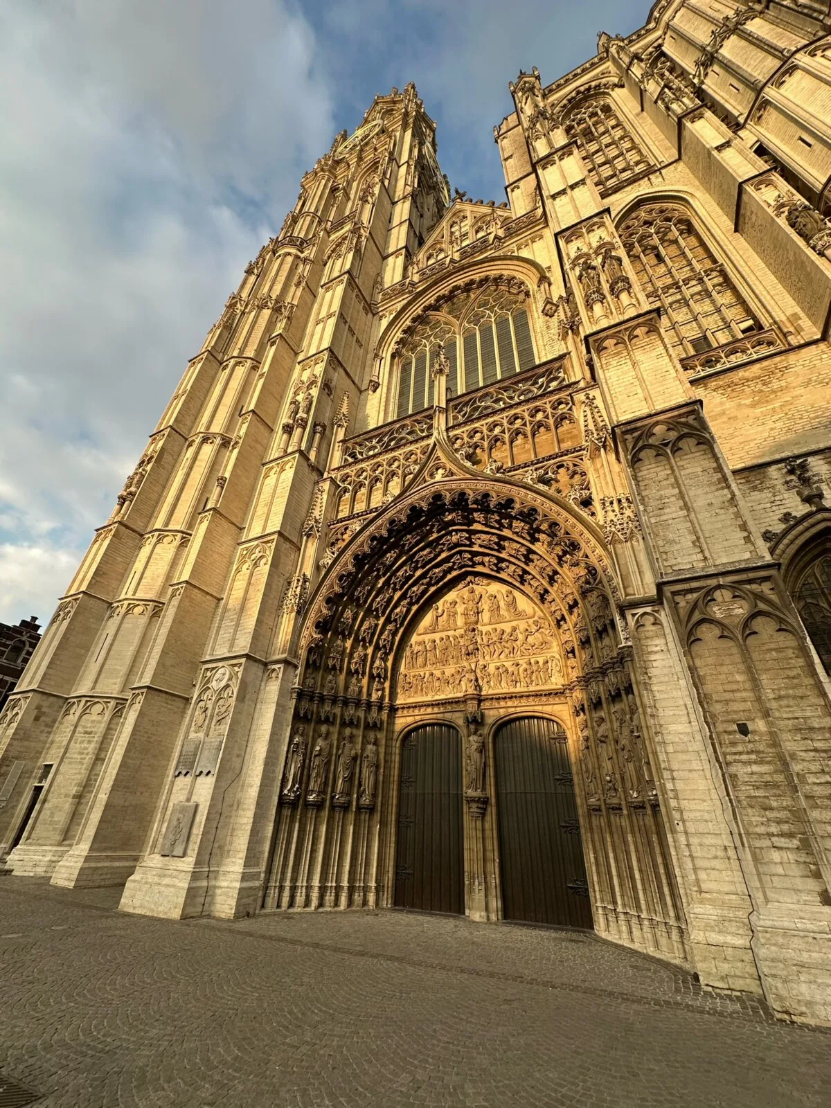 The Gothic facade and tower of the Cathedral of Our Lady in Antwerp under a blue sky